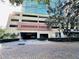 Parking garage entrance area of a building with brick paving, manicured shrubs, and surrounding trees at 101 S Eola Dr # 720, Orlando, FL 32801
