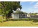 The backyard features mature trees, grassy area, and white siding on the detached home at 1016 E Fillmore Ave, Orlando, FL 32809