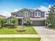 Charming two-story home featuring a stone facade, manicured landscaping, and a paved driveway at 1078 Vinsetta Cir, Winter Garden, FL 34787