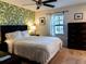 Inviting bedroom featuring a queen bed, ceiling fan, and accent wall with palm leaf wallpaper at 110 S Primrose Dr, Orlando, FL 32803