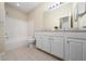 Bright bathroom featuring a tub with tile surround, a large mirror, and a white vanity at 12107 Poppy Field Ln # 105, Orlando, FL 32837