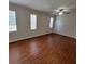 Bright, empty room with wood-look floors, ceiling fan and three large windows at 1325 Rotonda Pt # 117, Lake Mary, FL 32746