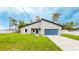 Charming single-story home featuring a blue garage door, well-kept lawn, and a modern roof design at 14957 Sw 63Rd Court Rd, Ocala, FL 34473