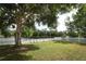 Serene backyard with picket fence bordering a calm lake and a shady tree at 1645 Boulder Creek Ct, Apopka, FL 32712