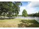 Fenced backyard features lush lawn, large tree, and serene lake view at 1645 Boulder Creek Ct, Apopka, FL 32712