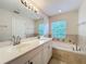 Bright bathroom features a double vanity and a soaking tub with tile surround at 1772 Garden Sage Dr, Oviedo, FL 32765