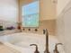 Bathroom soaking tub with tiled surround and a large window at 1772 Garden Sage Dr, Oviedo, FL 32765