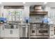 Bright kitchen with stainless steel appliances, farmhouse sink, patterned backsplash, and custom vent hood at 2105 Fosgate Dr, Winter Park, FL 32789