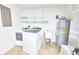 Bright laundry room features new washer and dryer units, shelving, water heater and wash basin at 211 Marion Oaks Ln, Ocala, FL 34473