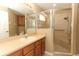 Neutral bathroom with a tiled shower, safety bar, glass door, oak vanity and cabinets at 212 Regency St, Davenport, FL 33896