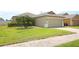 Single-story home featuring a two-car garage, well-maintained lawn, and a palm tree at 212 Regency St, Davenport, FL 33896