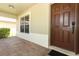 Covered entryway featuring a solid front door, keypad entry, and red brick style walkway at 212 Regency St, Davenport, FL 33896