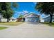 Single-story home with an attached garage and landscaped front yard with trees under a bright blue sky at 2709 Prestwick Ln, Kissimmee, FL 34744