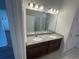 Bathroom with double sinks, granite countertops, and vanity lighting above the large mirror at 3408 Curlew Ave, Leesburg, FL 34748