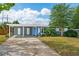 Street view of a charming home featuring a bright blue door, covered parking, and mature landscaping at 3520 Sebring Ave, Orlando, FL 32806
