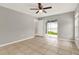 Neutral bedroom with tile floors, ceiling fan, and sliding glass doors to the screened patio at 4347 Creekside Blvd, Kissimmee, FL 34746