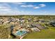 An aerial view features the community pool, splash pad, playground, and surrounding homes against a blue sky at 4591 Gliding Wave St, Winter Garden, FL 34787