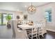 Cozy dining area with chandelier, white wood table, and seamless flow to the living room with large windows at 4591 Gliding Wave St, Winter Garden, FL 34787