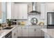 Well-lit kitchen boasts white cabinetry, stainless steel appliances, granite counters, and a tiled backsplash at 4591 Gliding Wave St, Winter Garden, FL 34787