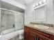 Bathroom featuring tub with glass doors, vanity with granite countertop, and modern fixtures at 5481 Nokomis Cir, Orlando, FL 32839