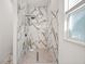 Modern shower with marble tiling and a pebble floor, and natural light from a window at 600 Lakewood Ave, Ocoee, FL 34761