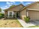 Home featuring a two-car garage, well-kept lawn, and an inviting front entrance with some foliage at 6701 Belmar Dr, Orlando, FL 32807