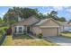 Home featuring a two-car garage, well-kept lawn, and an inviting front entrance with some foliage at 6701 Belmar Dr, Orlando, FL 32807