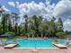 Outdoor swimming pool surrounded by lounge chairs, green foliage, and a trellis at 7010 Broomshedge Trl, Winter Garden, FL 34787