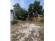 Overgrown backyard features gravel, vehicle, wood debris, a fence, and glimpses of the home's exterior at 7506 Mott Ave, Orlando, FL 32810