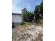View of the backyard area with gravel, a vehicle, wood pile, and a partial view of the house at 7506 Mott Ave, Orlando, FL 32810