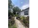 Image captures a home's backyard with lush vegetation, a pathway, exterior view, and some garden items at 7506 Mott Ave, Orlando, FL 32810