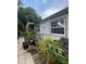 Image of the home's side with lush vegetation, garden items, and a stone foundation at 7506 Mott Ave, Orlando, FL 32810