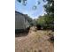 Shows the side of the home with faded siding, overgrown landscape, and a trailer at 7506 Mott Ave, Orlando, FL 32810