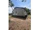 Shows the rear of the home with faded siding and an unkempt yard at 7506 Mott Ave, Orlando, FL 32810
