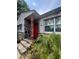 Inviting home featuring a stone facade, red door, and lush tropical landscaping at 7506 Mott Ave, Orlando, FL 32810