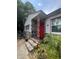Charming home featuring a stone facade, red door, and decorative support beams at 7506 Mott Ave, Orlando, FL 32810