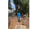 A blue water pressure tank and pump sit on a bed of leaves beneath trees in the backyard at 7506 Mott Ave, Orlando, FL 32810