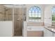 Bathroom featuring tiled shower, soaking tub under an arched window with water view, and granite countertop vanity at 850 Spring Oak Cir, Orlando, FL 32828