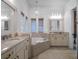 Bright bathroom features a soaking tub, granite counters, neutral cabinets, and decorative chandelier at 960 Golden Bear Dr, Reunion, FL 34747