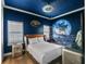 Space-themed bedroom featuring a custom bed, mural, ceiling fan, and decor at 960 Golden Bear Dr, Reunion, FL 34747