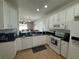 A kitchen featuring white cabinetry, black countertops, and stainless-steel appliances, with views to a dining area at 9959 Cypress Vine Dr, Orlando, FL 32827