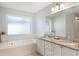 Elegant primary bath featuring a soaking tub, double sink vanity with granite countertops, and bright lighting at 1018 Featherstone Cir, Ocoee, FL 34761