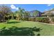 Expansive backyard featuring a lush lawn, tropical landscaping, and a screened lanai at 11502 Waterstone Loop Dr, Windermere, FL 34786