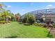 Lush backyard with mature landscaping, green lawn, and a screened lanai with pool at 11502 Waterstone Loop Dr, Windermere, FL 34786