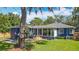 Back of house with a glass sunroom, a wooden deck, and a spacious grassy yard, all in a well-kept landscape at 1202 Chichester St, Orlando, FL 32803