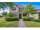 Charming two-story home showcasing verdant landscaping, shrubs, and a brick walkway at 16043 Pebble Bluff Loop, Winter Garden, FL 34787