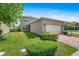 Side view of the garage and driveway with lush green landscaping and blue sky at 16043 Pebble Bluff Loop, Winter Garden, FL 34787