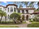 Elegant two-story home showcasing stucco facade, arched windows, balconies, and a landscaped walkway at 1716 Greystone Ct, Longwood, FL 32779