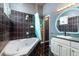 This bathroom features black tiled walls, a bathtub, and a vanity with a round mirror at 1718 Elaine Ave, Altamonte Springs, FL 32701