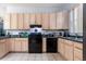 Kitchen features bright wood cabinets, black appliances, and ceramic tile flooring at 1718 Elaine Ave, Altamonte Springs, FL 32701